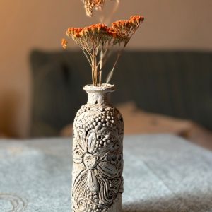 Pequeña botella de cristal adornada con arcilla